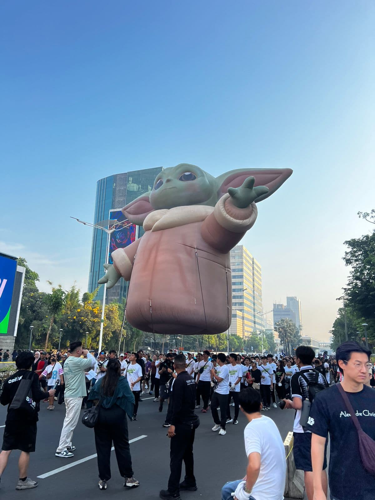 Inflatable helium Grogu yang besar terapung di atas orang ramai dalam perarakan jalanan, dibina untuk Disney Indonesia