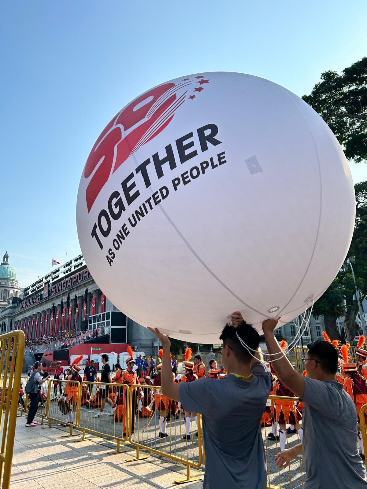 Sfera SG59 gergasi bercetak Together as One United People, dibawa oleh krew di Perarakan Hari Kebangsaan Singapura