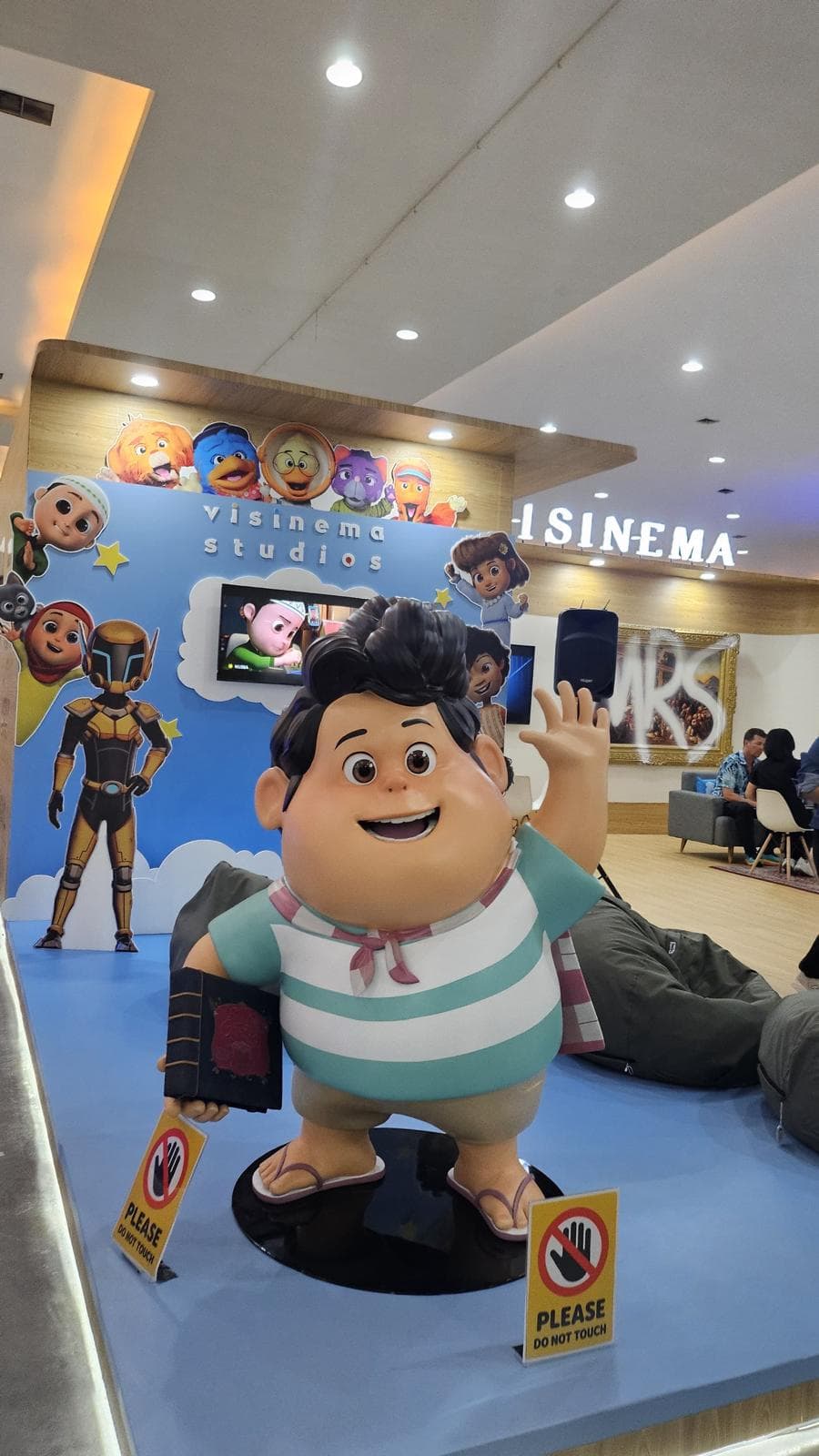 Model Don dari filem animasi Jumbo, dibina untuk Visinema Studios, melambai sambil memegang buku di gerai pameran studio