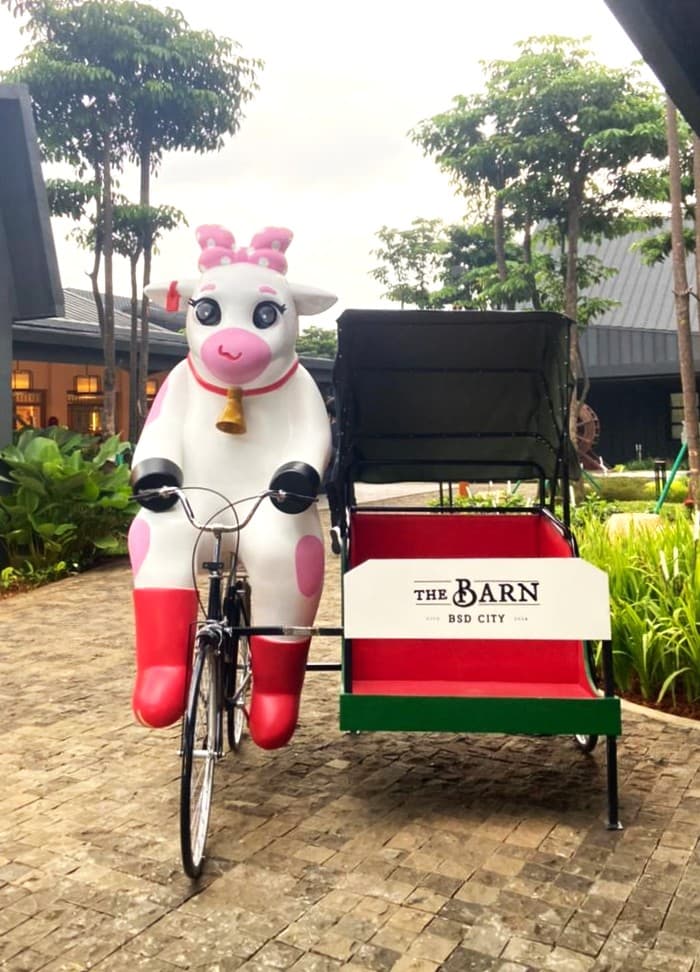 Model lembu merah jambu dan putih menunggang beca di luar The Barn, BSD City, Indonesia